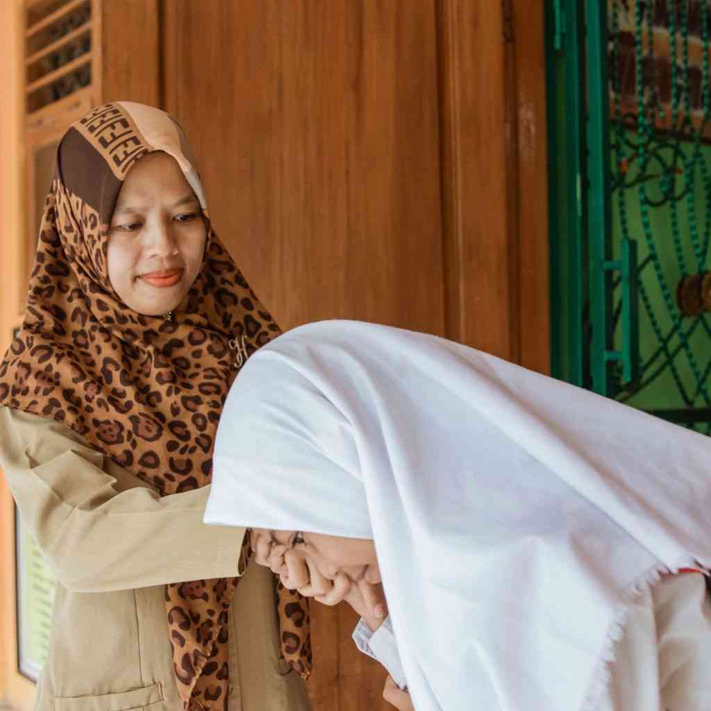 Seorang siswi sedang bersalaman dan berpamitan pulang kepada ibu guru (elibrary.id)