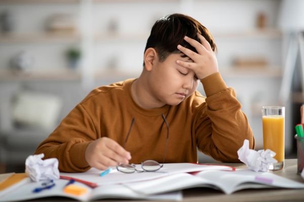 Seorang anak pusing karena mengerjakan tugas sekolah yang cukup sulit
