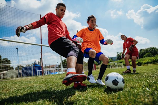 Bermain sepak bola di lapangan berumput
